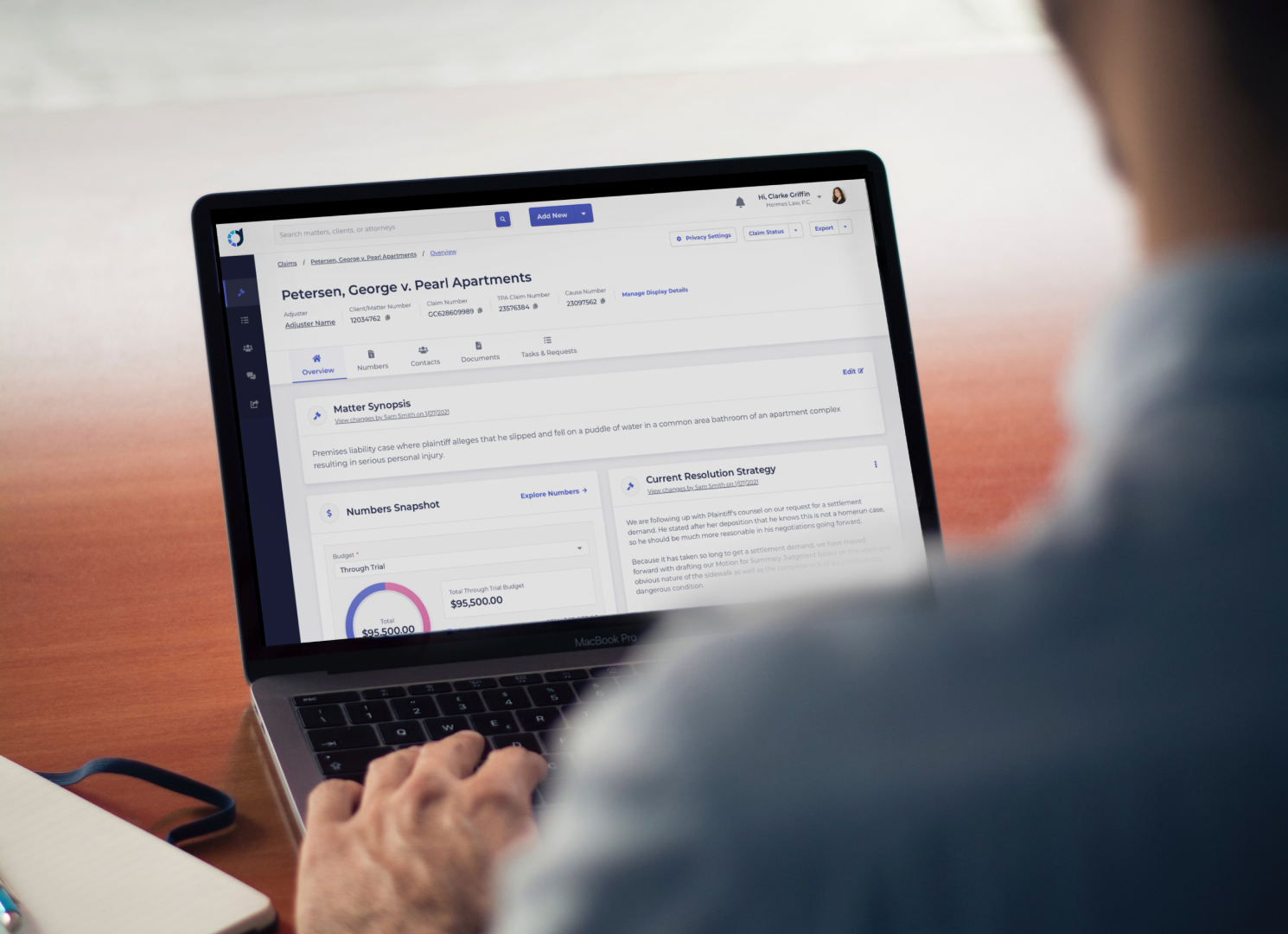 Legal professional using Claimdeck litigation management software on a MacBook Pro to manage insurance claims.
